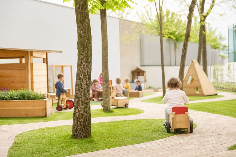 Bambina che guarda dentro un cannocchiale azzurro installato in uno spazio gioco all'aperto